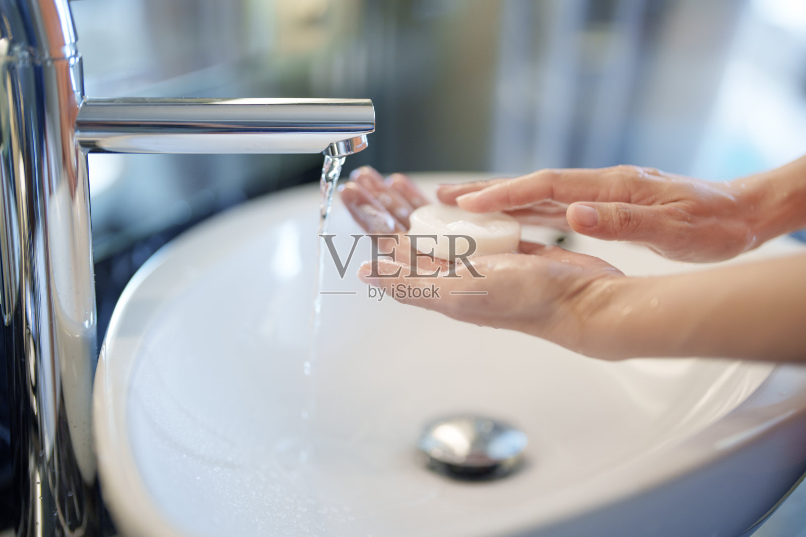 一名妇女在水槽中用肥皂洗手，以保持手部卫生。照片摄影图片