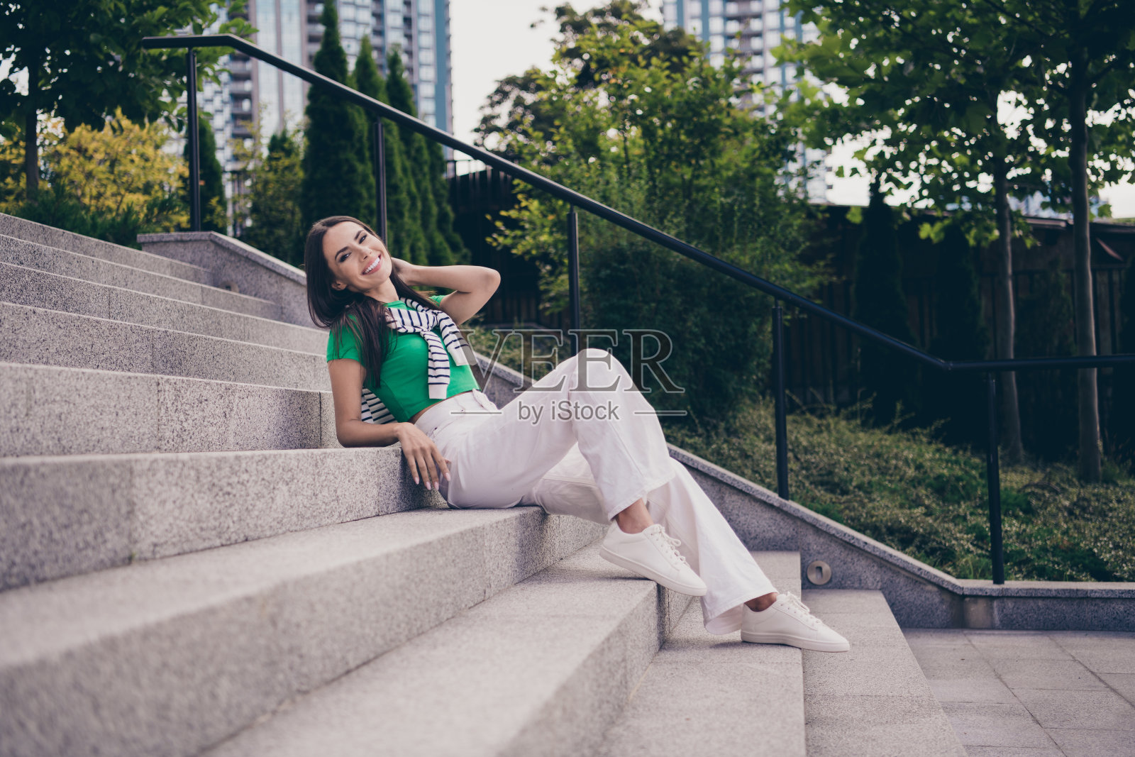 积极可爱的女人穿着时髦的衣服坐在公园的楼梯上享受春天的户外自由时光照片摄影图片