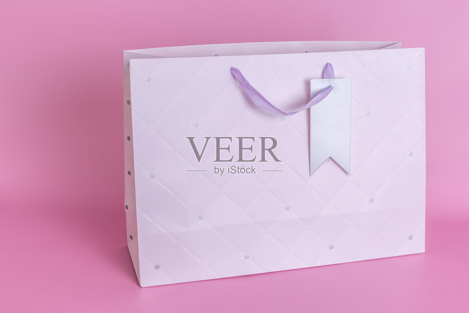 一个干净的大纸袋和把手矗立在粉红色的特写背景上。照片摄影图片