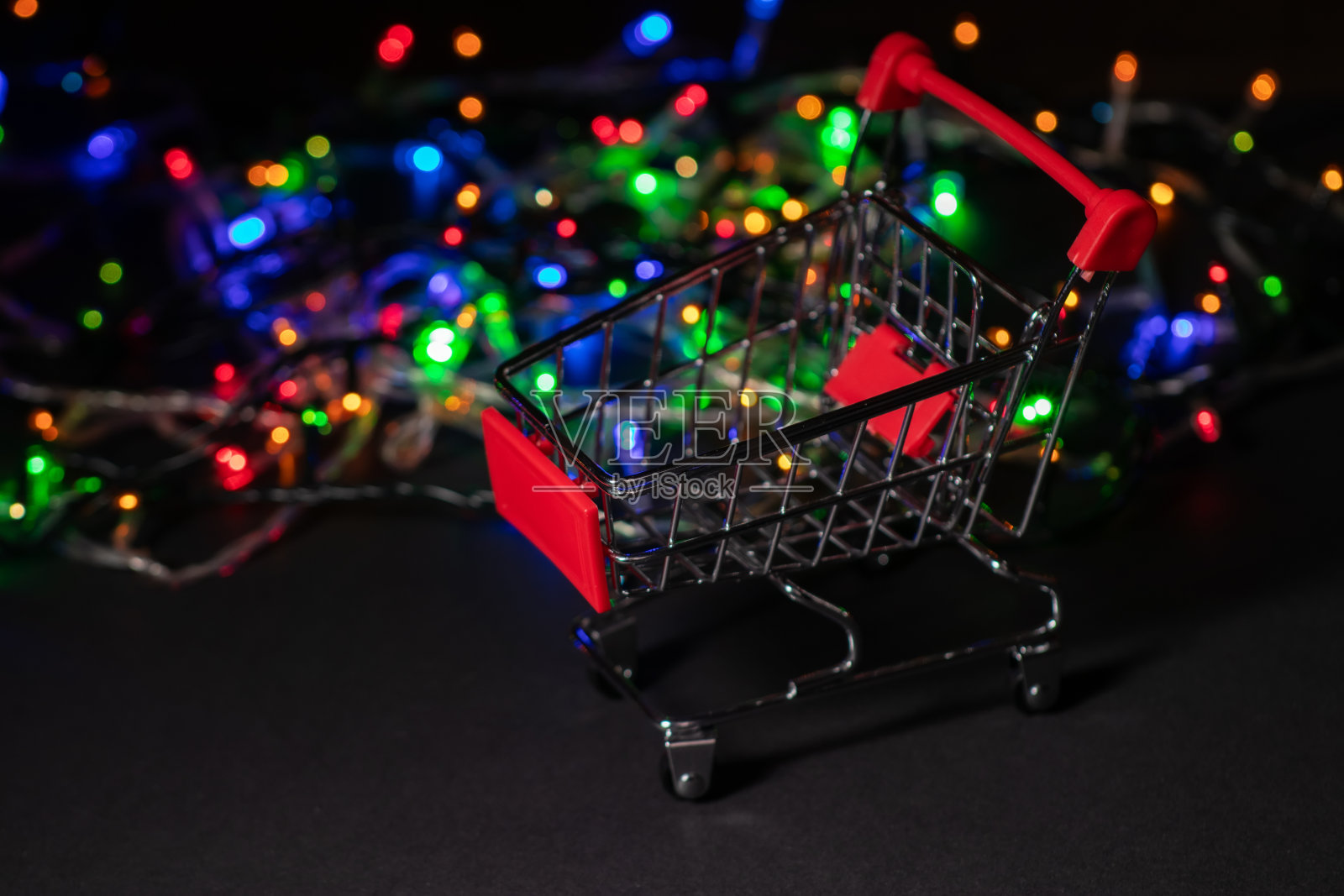 新年购物。购物车上的圣诞花环光的背景。照片摄影图片