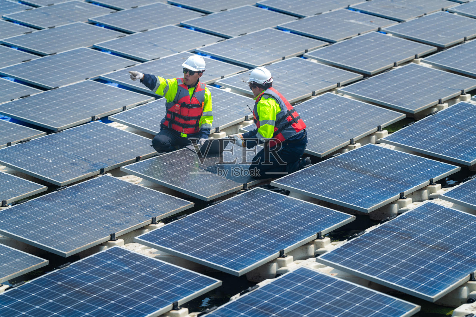 光伏工程师研究浮动光伏。工人检查和修理漂浮在水面上的太阳能电池板设备。工程师在湖面上安装浮动太阳能板平台系统。照片摄影图片