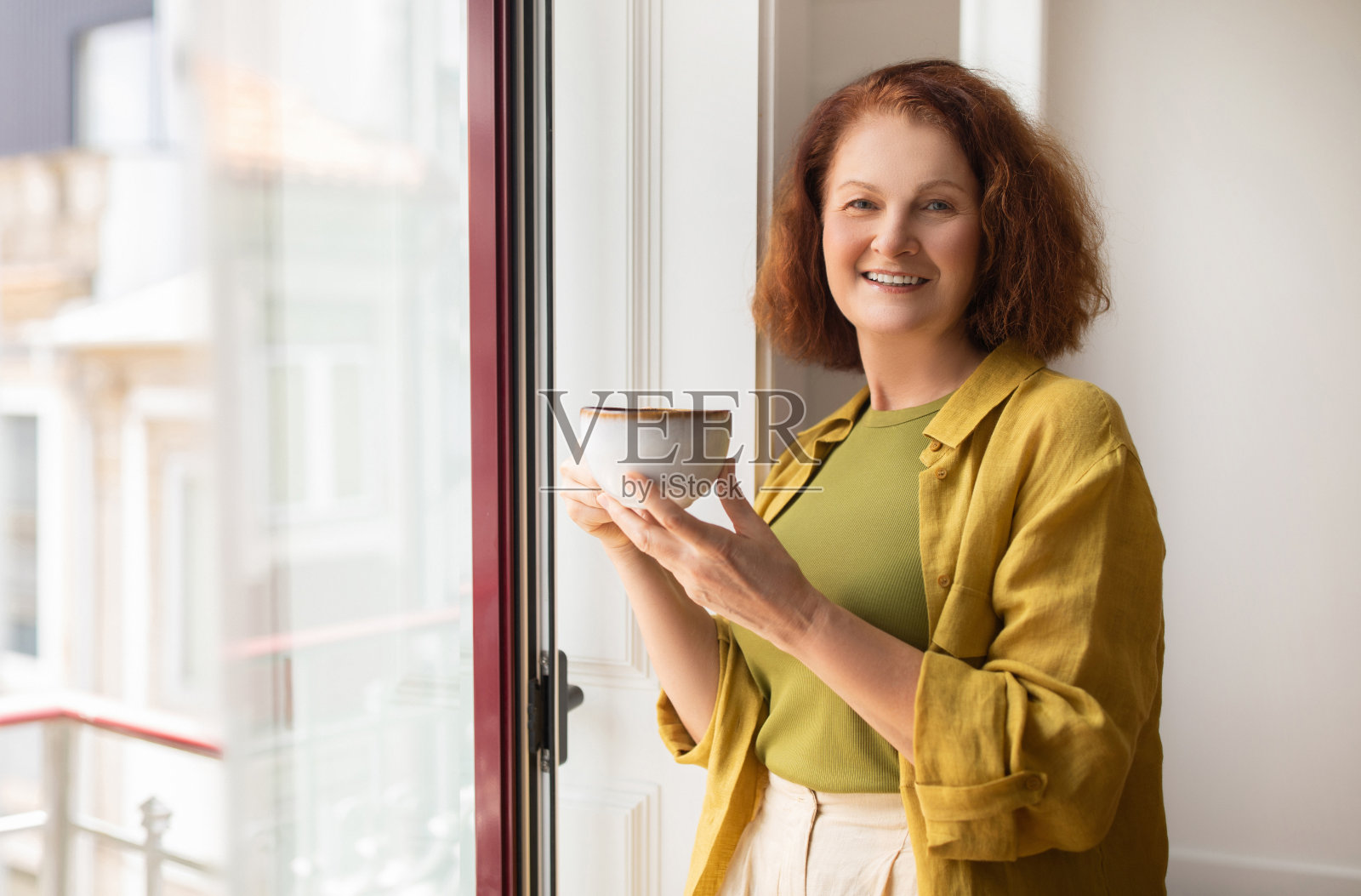 漂亮的老女人站在窗边喝咖啡照片摄影图片