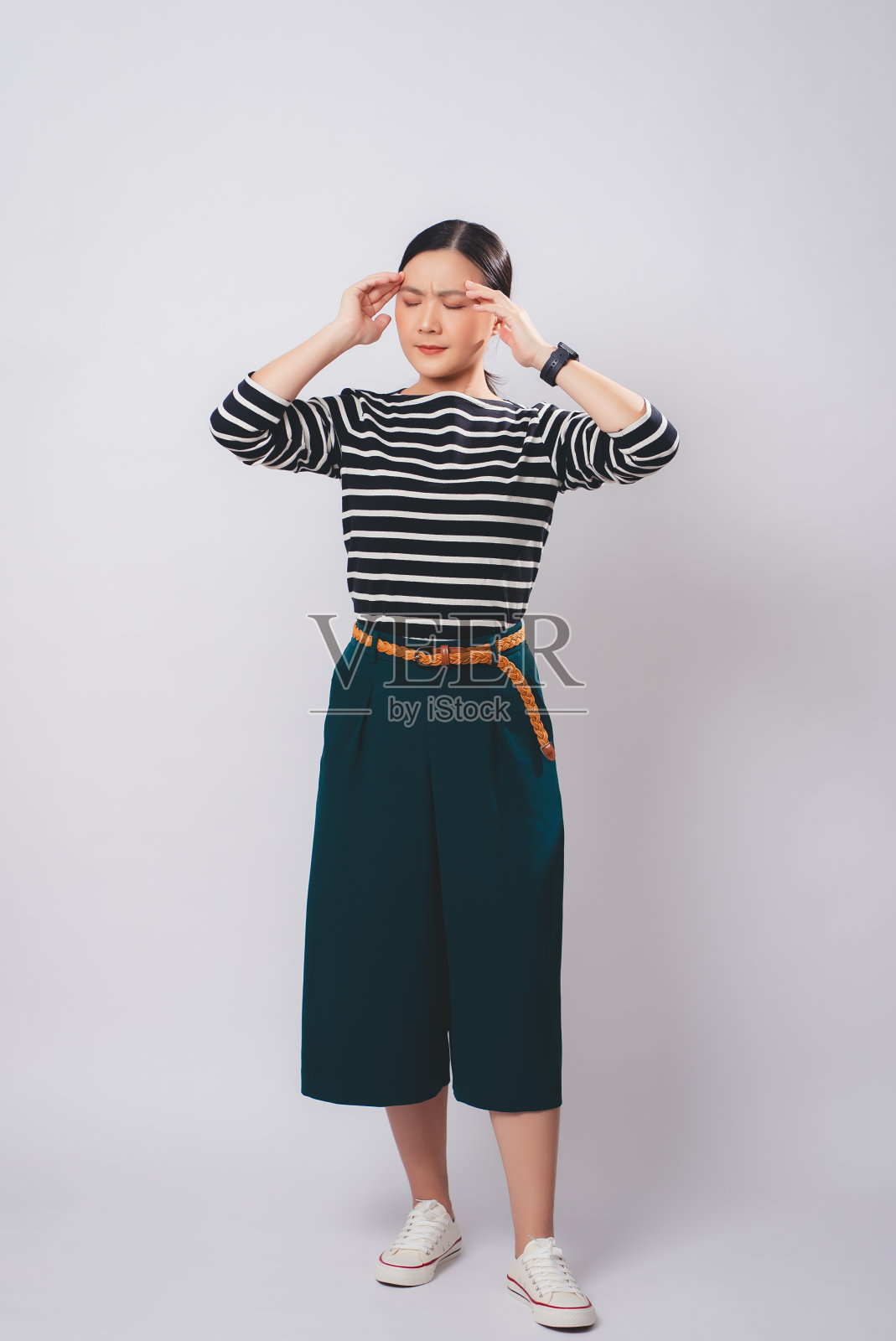 一名亚洲妇女患头痛，独自站在白色背景上。照片摄影图片