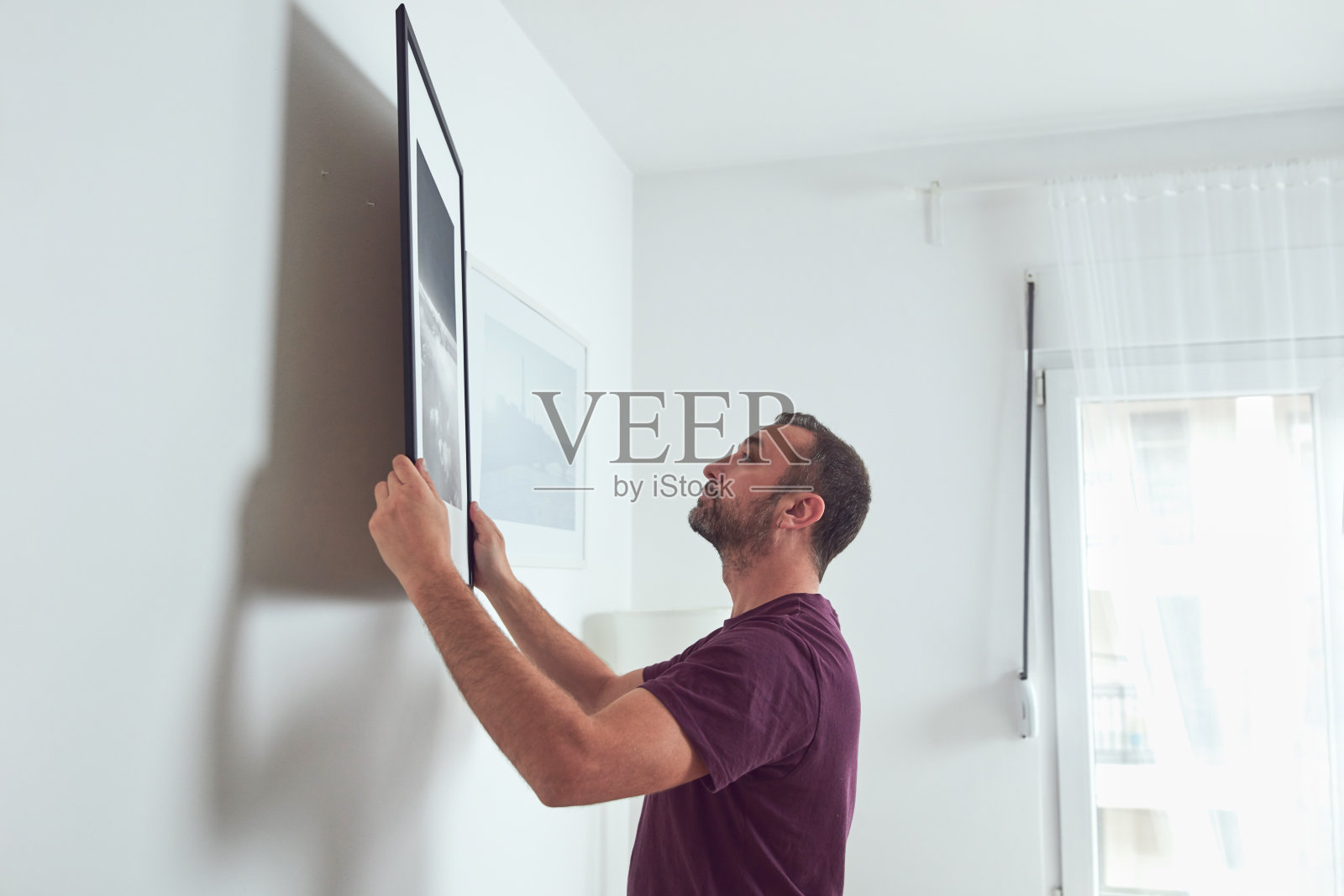 男人在墙上挂画，打扫和改造公寓。照片摄影图片