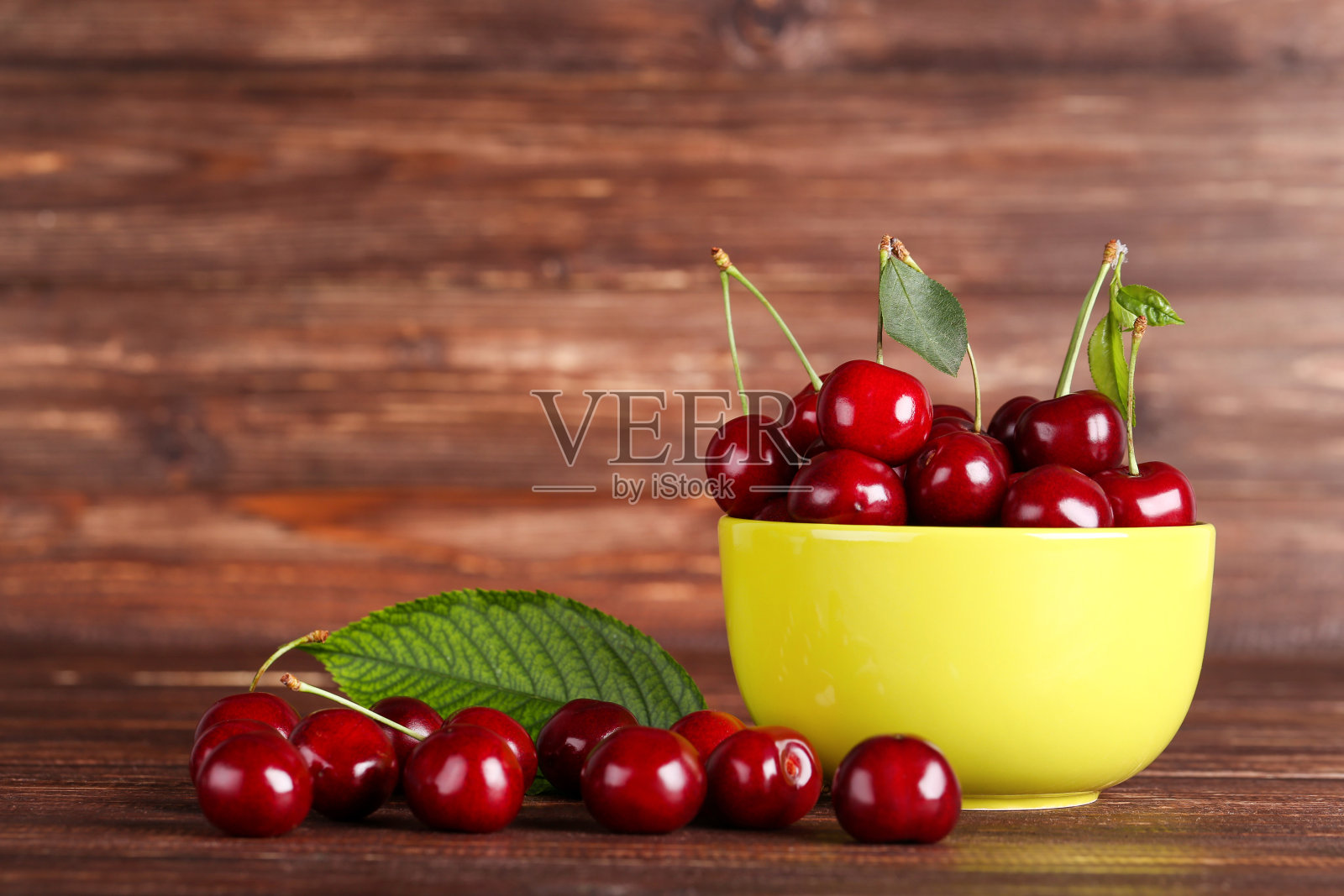棕色木桌上碗里的甜樱桃照片摄影图片