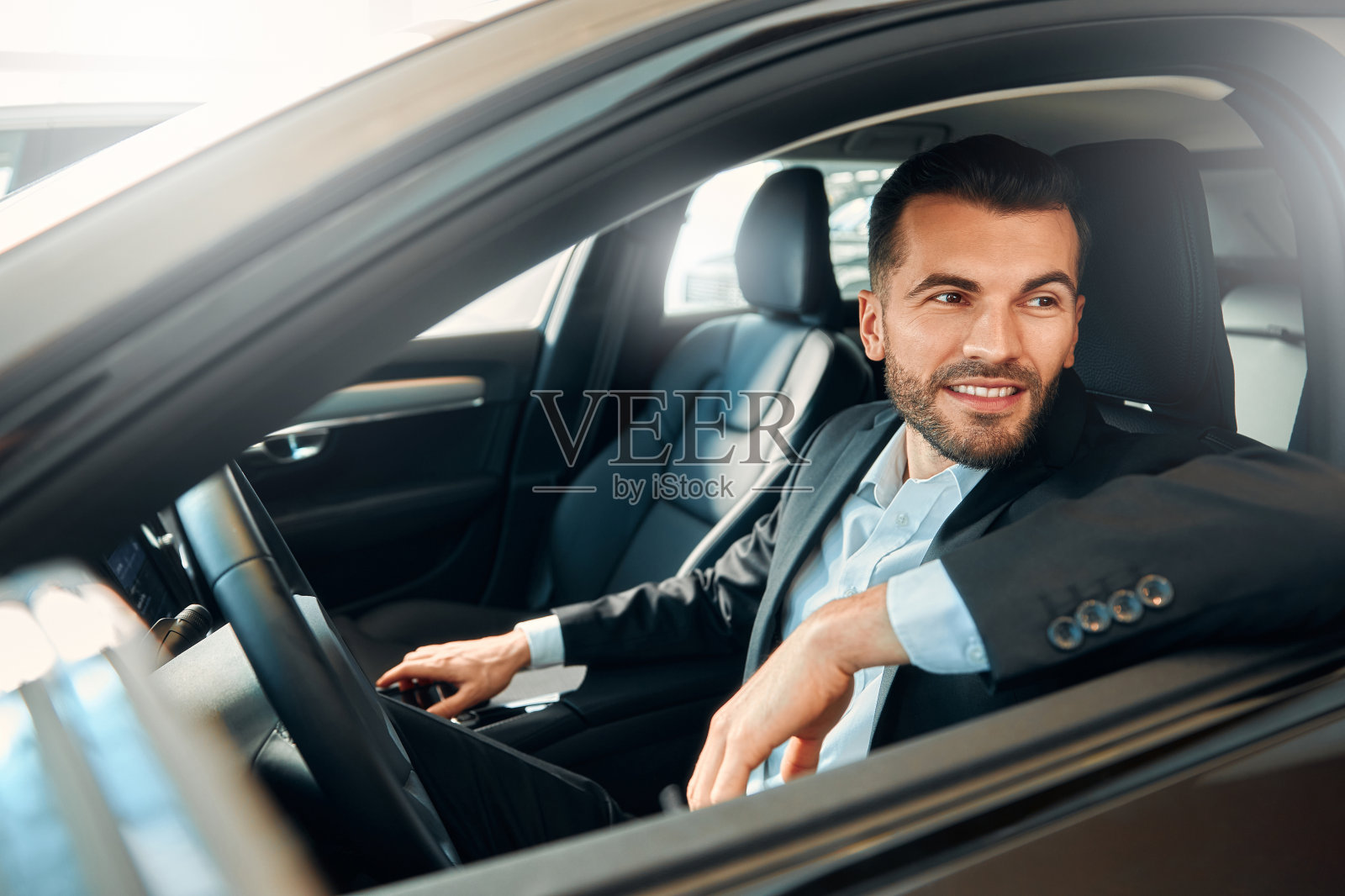 穿着黑色西装坐在车里的商人。照片摄影图片