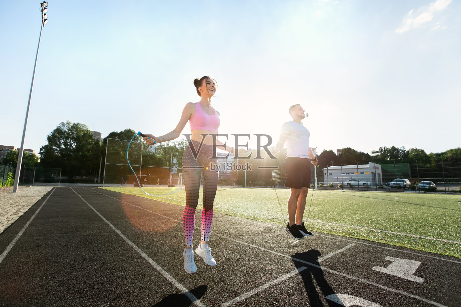 年轻的健身夫妇在日落时分在户外玩跳绳。照片摄影图片