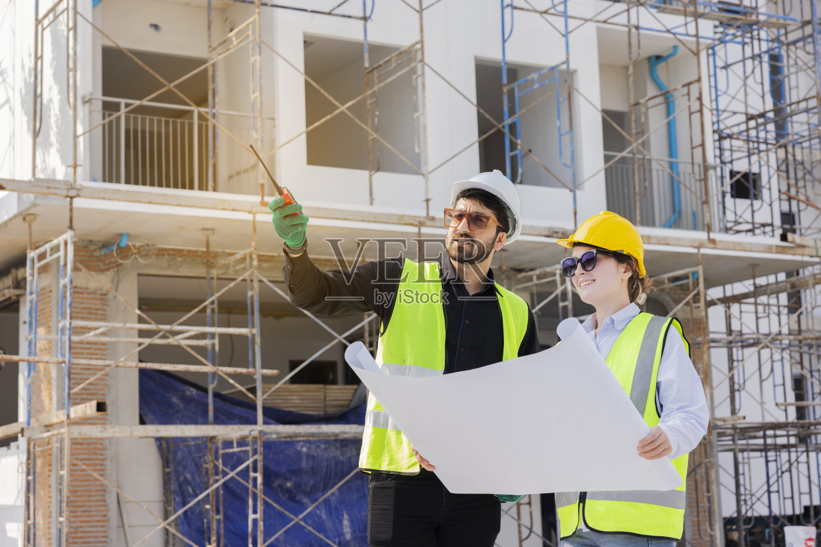 工程师和建筑师看白种人的建筑蓝图，规划工作在一个专业。检查员正在工地检查钢结构和材料。照片摄影图片