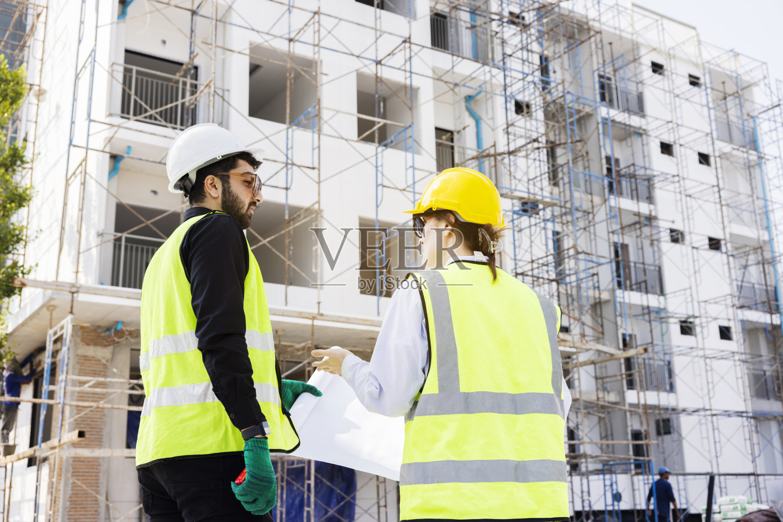 工程师和建筑师看白种人的建筑蓝图，规划工作在一个专业。检查员正在工地检查钢结构和材料。照片摄影图片