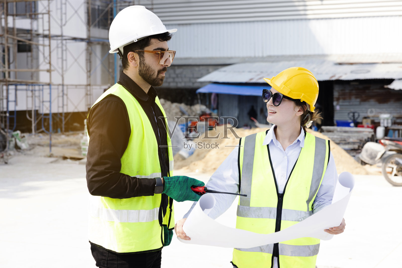 工程师和建筑师看白种人的建筑蓝图，规划工作在一个专业。检查员正在工地检查钢结构和材料。照片摄影图片