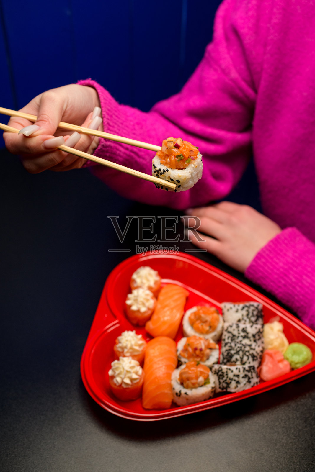 女性的手从心形寿司盒里拿着寿司卷照片摄影图片