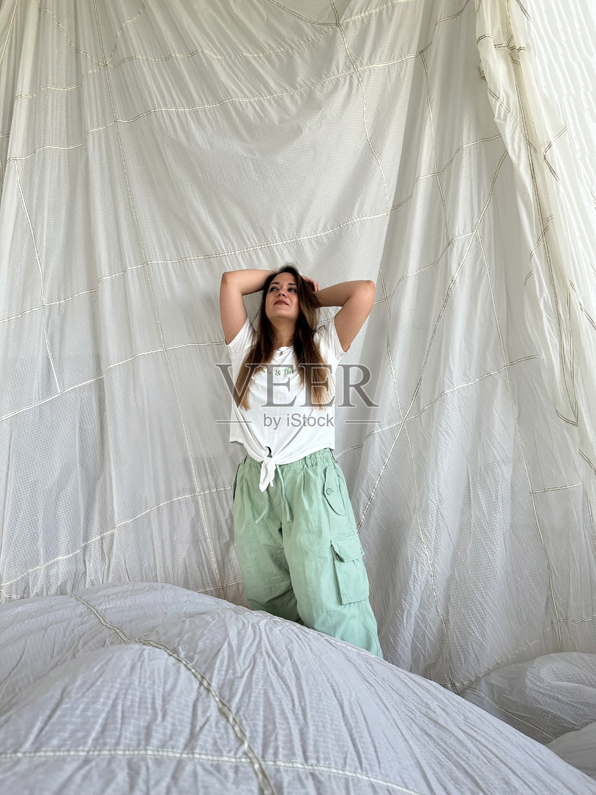 年轻漂亮的女人，长发，绿眼睛，纹身，背景是一个白色的降落伞照片摄影图片