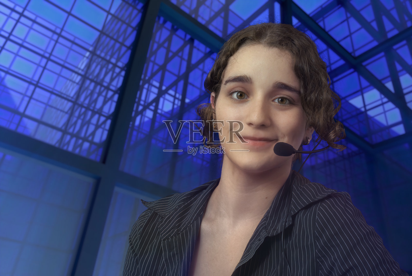 年轻的客户支持服务代表，戴着耳机的女接线员，戴着蓝色的玻璃窗户照片摄影图片