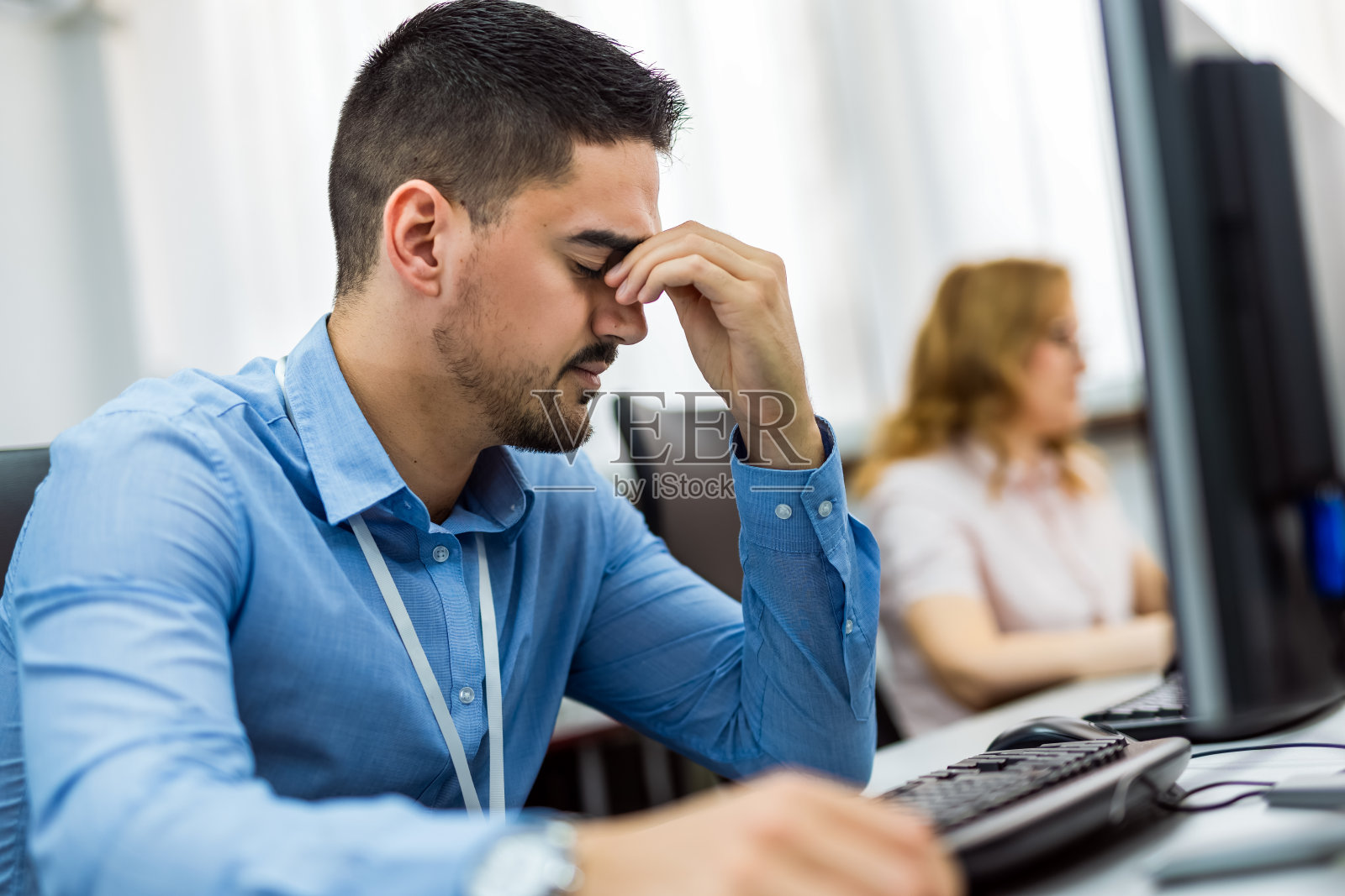 年轻英俊的商人正在办公室里努力地摆弄电脑照片摄影图片