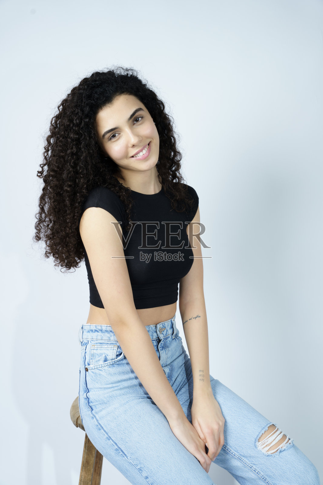 一个开朗、精力充沛的年轻女子，有着美丽的眼睛和卷曲的头发。影棚拍摄照片摄影图片