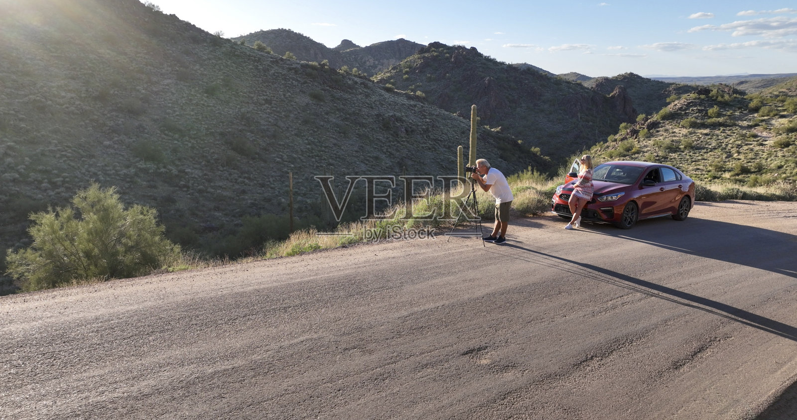 成熟的夫妇在日落时分把车停在沙漠里照片摄影图片