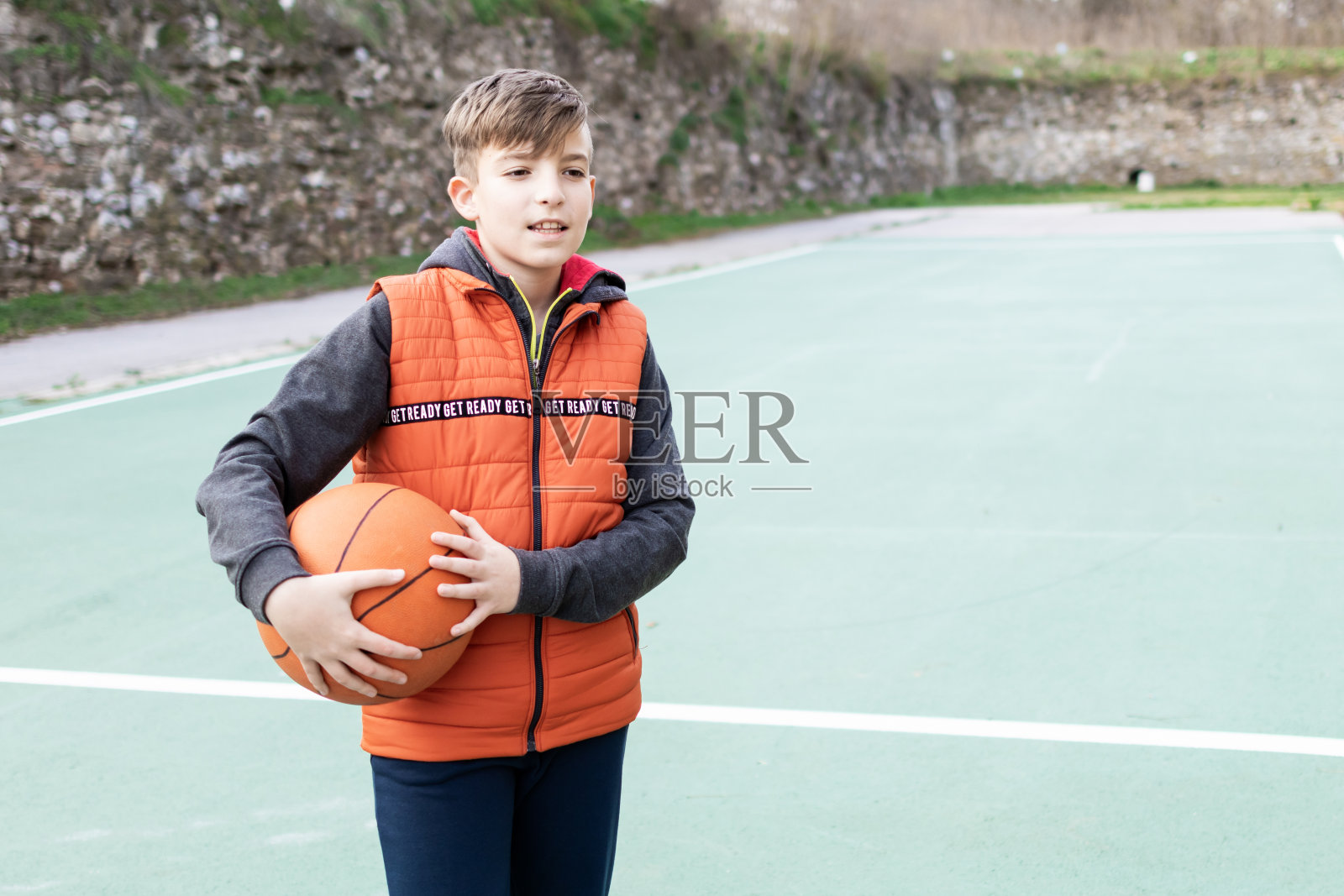 一个男孩在体育场上拿着篮球的照片。照片摄影图片
