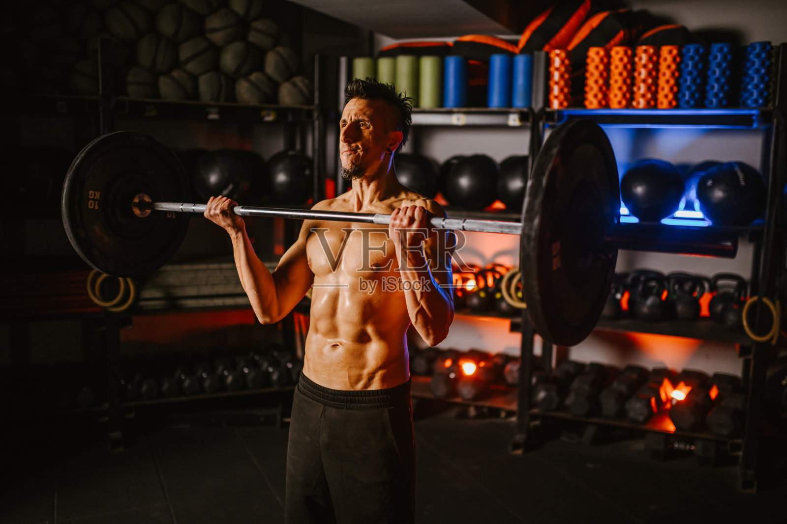 一个肌肉发达的健美运动员在健身房用杠铃做力量举。照片摄影图片