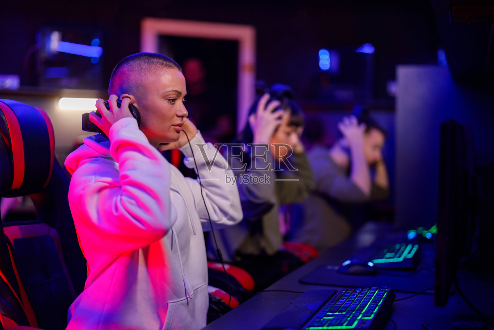 年轻的秃顶女玩家戴着耳机玩电子游戏照片摄影图片