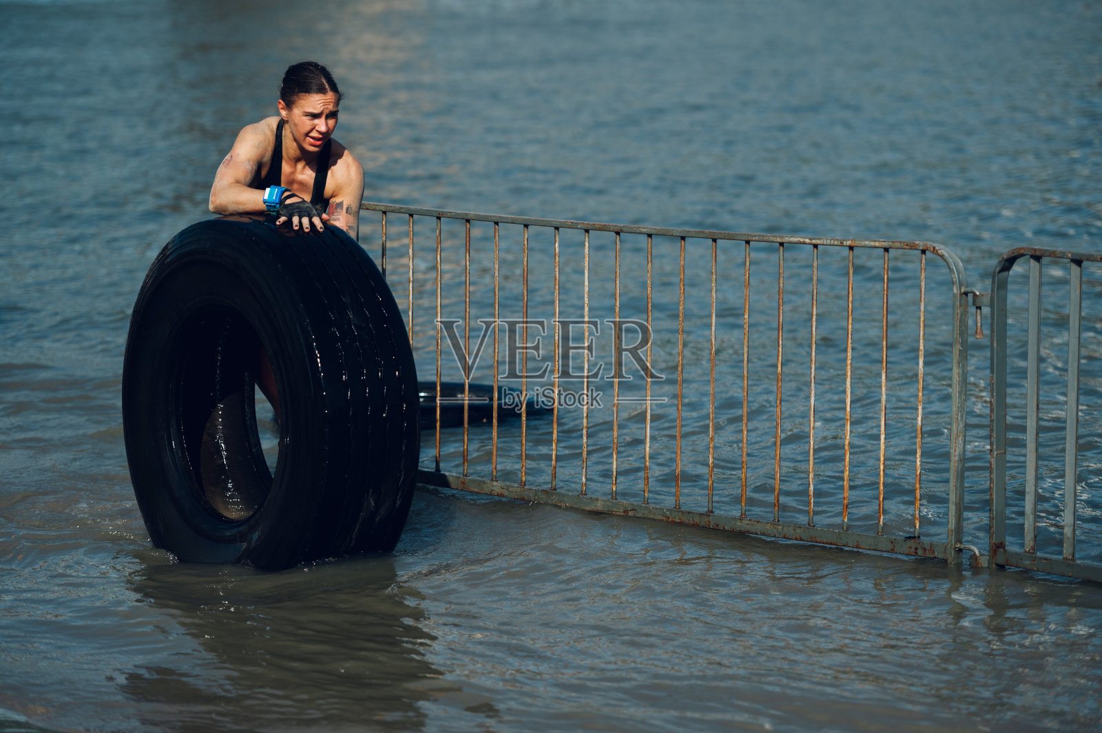 女子完成了一场OCR比赛，同时将拖拉机轮胎推出水面照片摄影图片