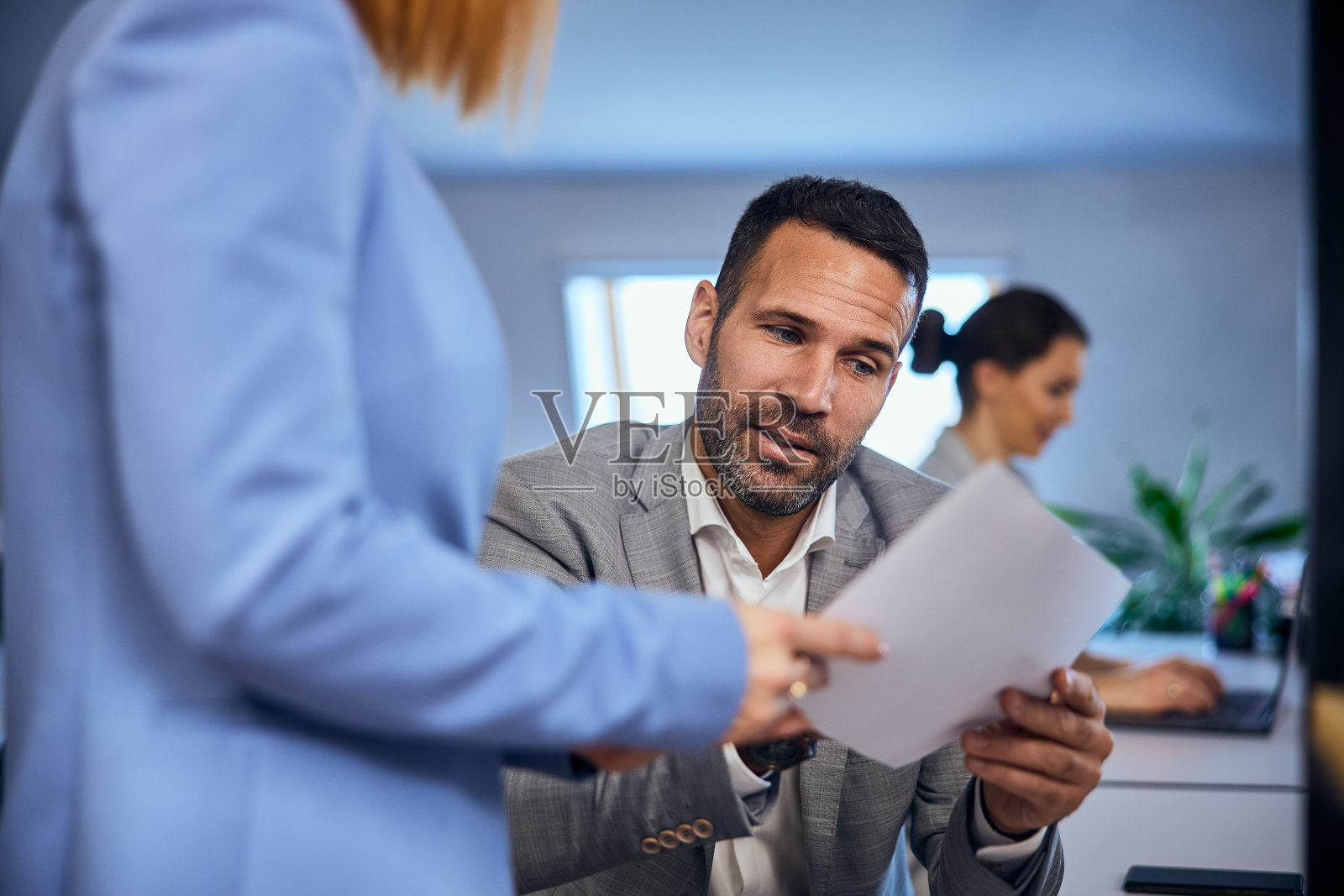 一个商人在办公室和她的女同事谈论那份文件。照片摄影图片