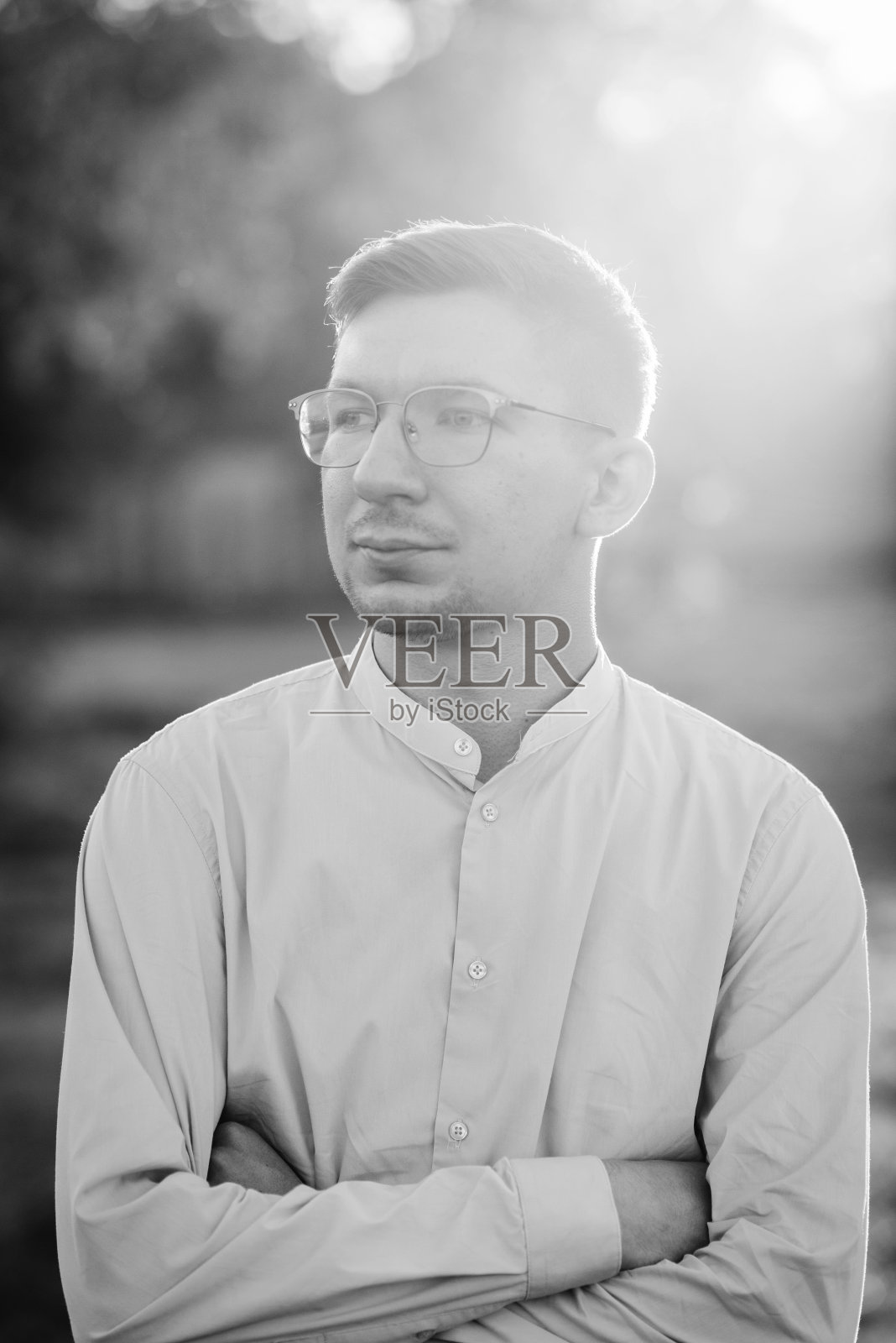 男性肖像在夏日的特写镜头中望向远方。一位戴眼镜的英俊男子站在夕阳下。在夕阳的背景下，严肃的男性出现在田野上。黑白照片照片摄影图片