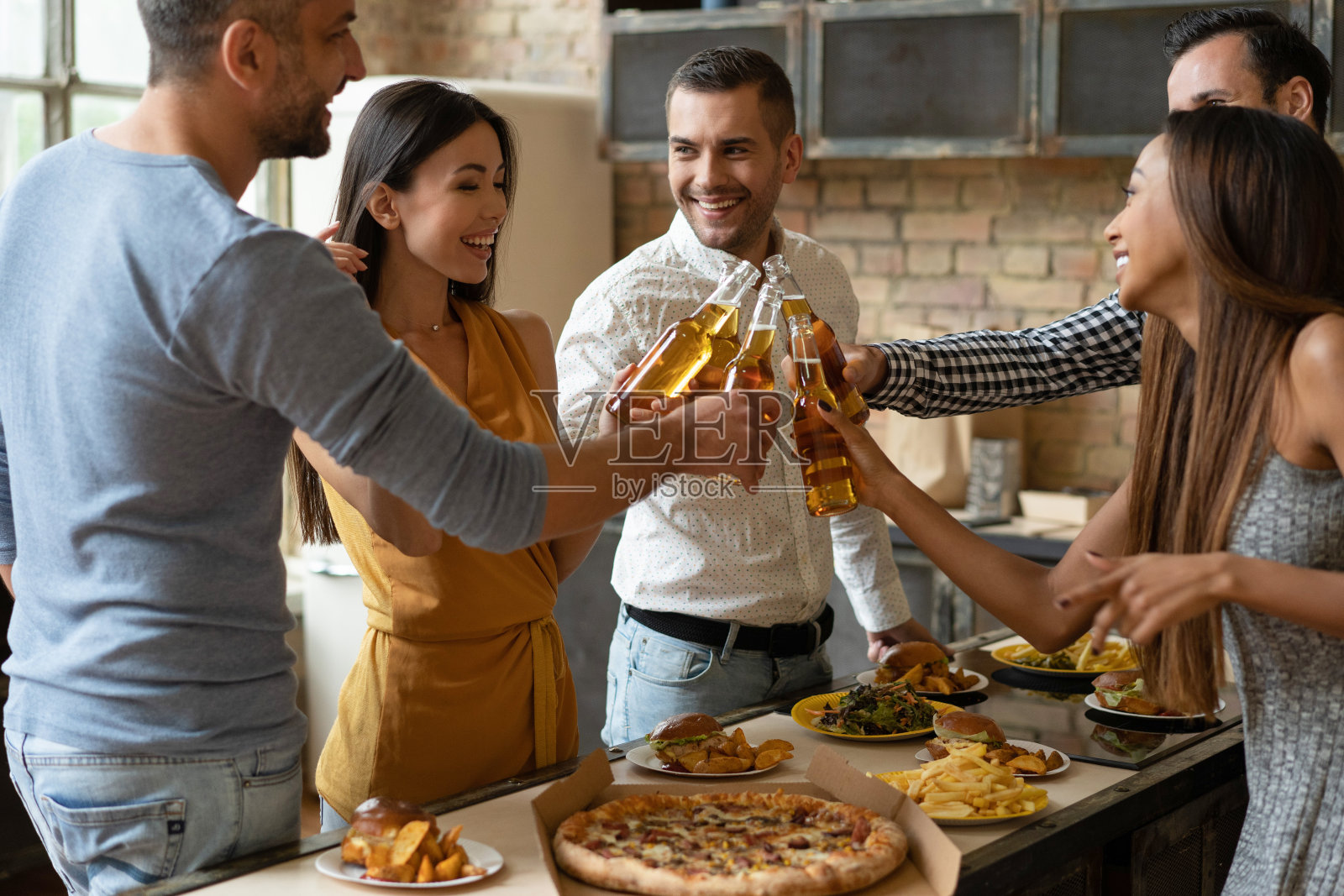穿着便服的漂亮年轻人拿着一瓶一瓶的饮料休息，谈笑风生。照片摄影图片