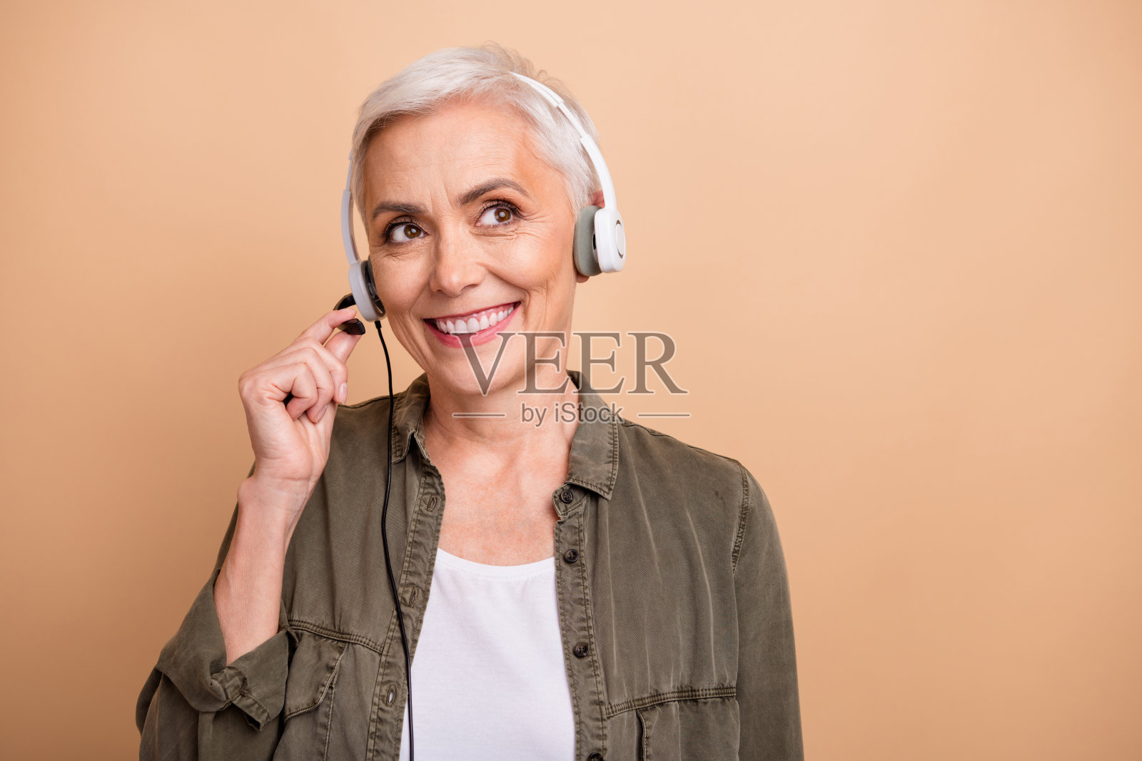 可爱的养老金领取者的照片肖像女士耳机看空空间穿时髦的卡其布服装孤立的米色背景照片摄影图片