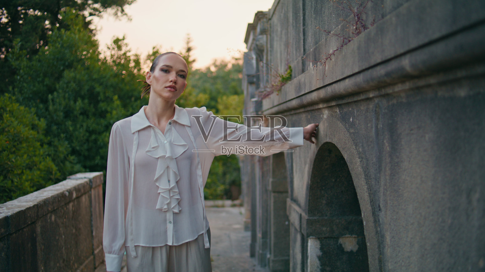 老太太摸着老墙，走着露台，废弃的城堡。漫步阳台的女人照片摄影图片