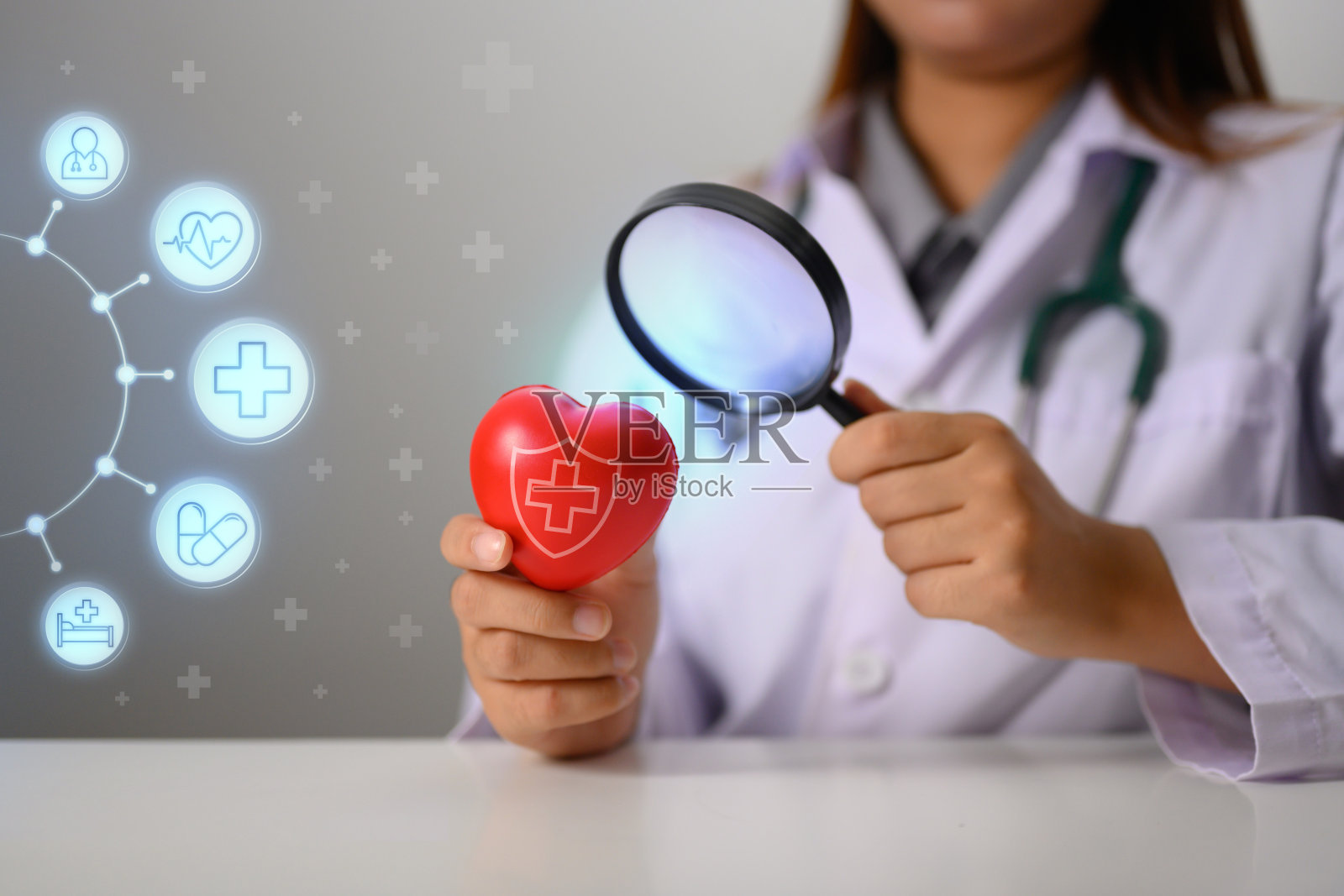 女心脏病专家拿着放大镜检查红心。健康保险和心脏病学概念照片摄影图片