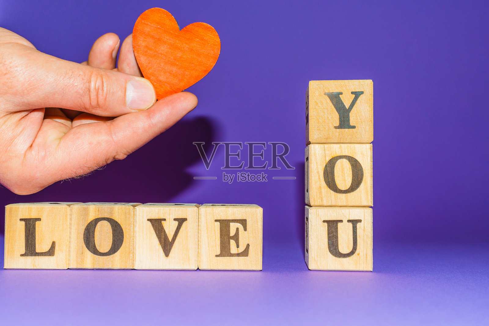 男掌心握心。我爱你的文字在木块紫色veri圆形背景。副本的空间。照片摄影图片