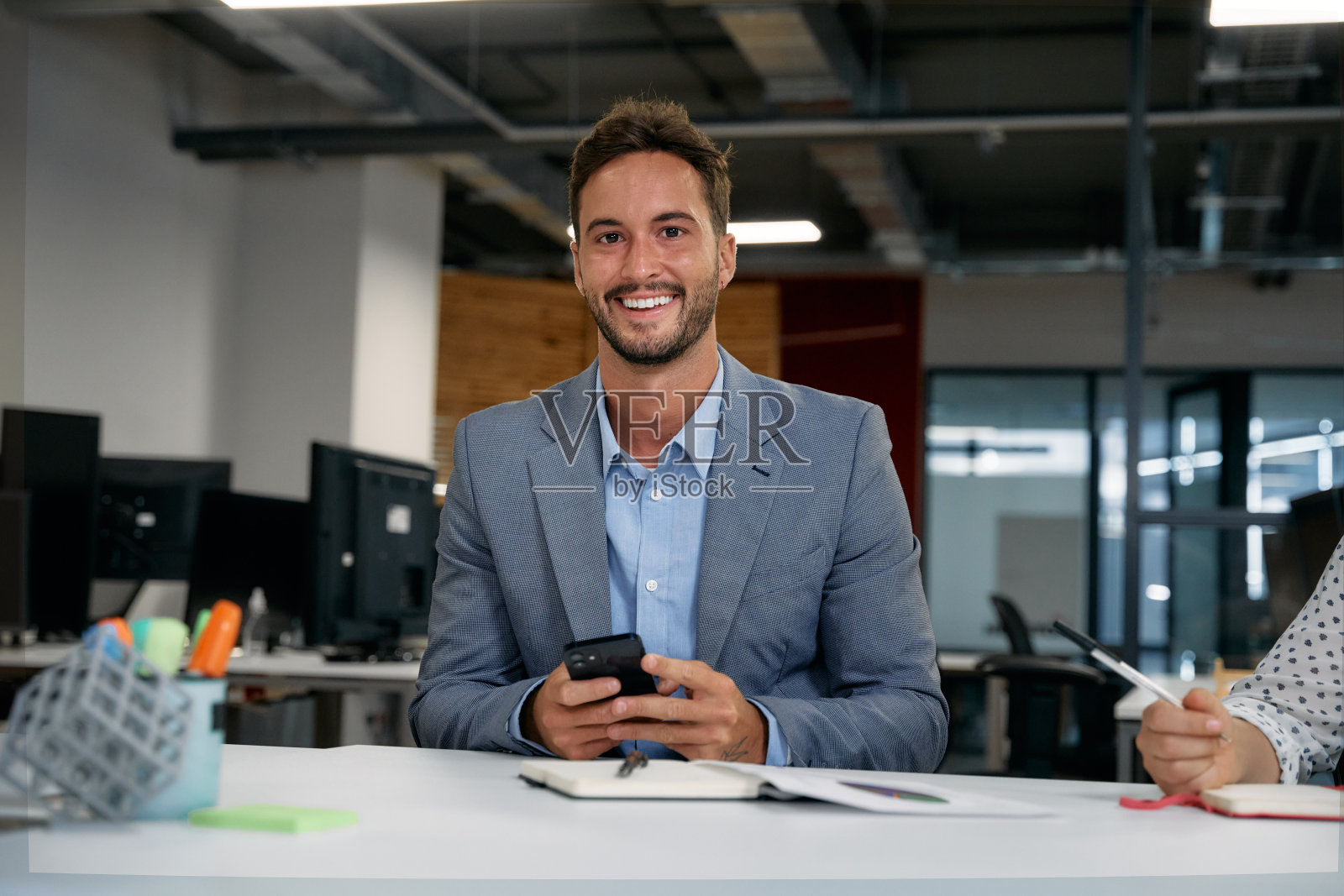 两个白人商人在办公室里用智能手机看着相机，微笑着照片摄影图片