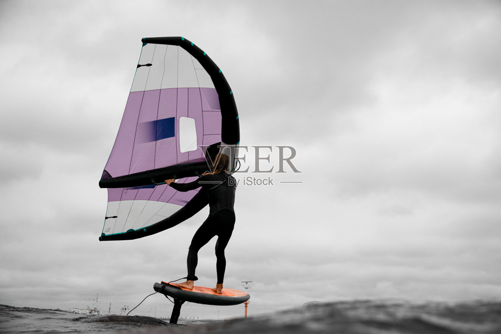 男性冲浪者站在船上，拿着翅膀进行翼折照片摄影图片