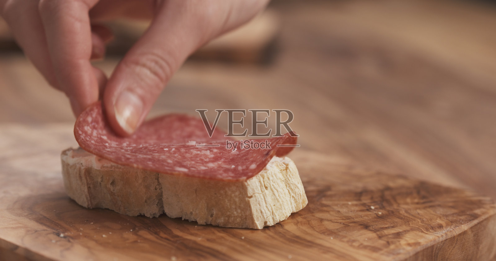 女手做三明治法棍片与奶油奶酪和意大利腊肠照片摄影图片