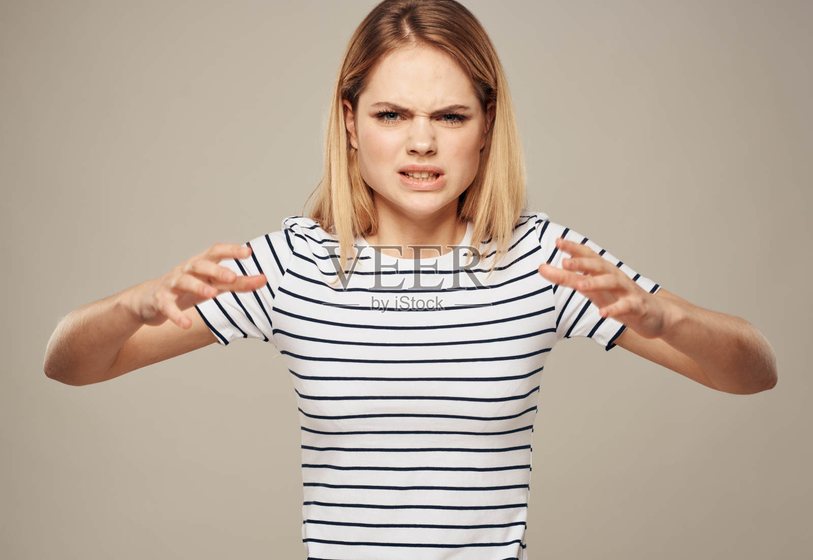 紧张的女人穿着条纹t恤，金色米色背景特写照片摄影图片
