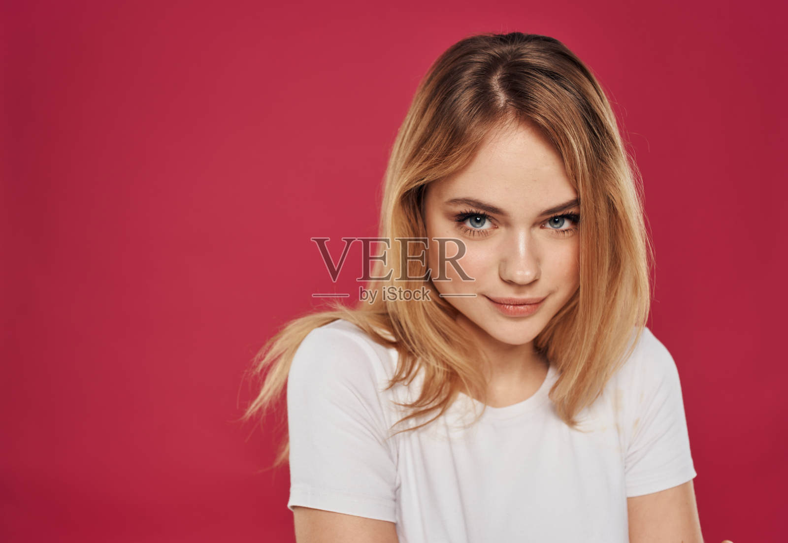 一个美丽的金发女郎的肖像在一个红色的背景上的白色t恤照片摄影图片