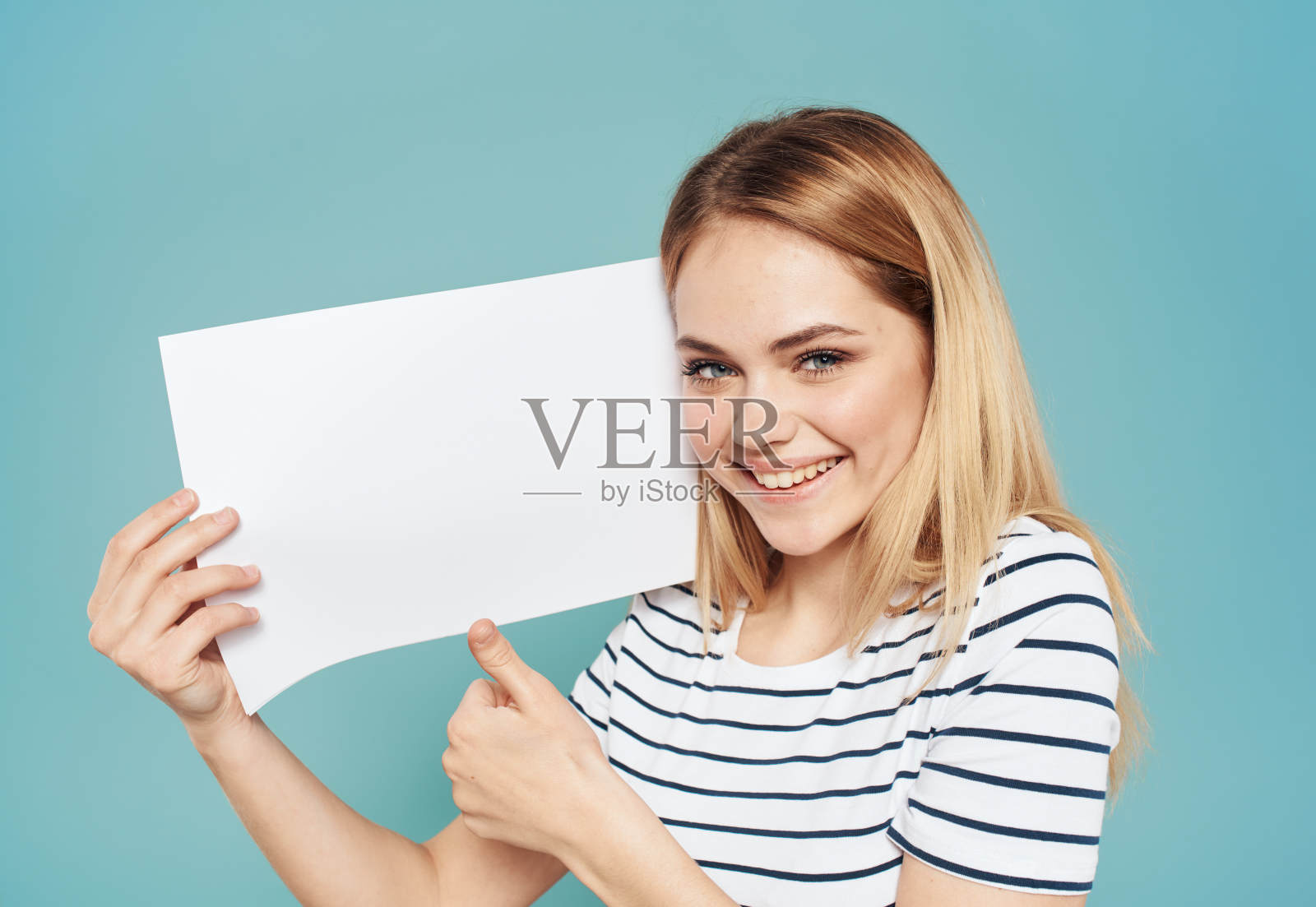 美丽的金发碧眼的蓝色背景与一张白纸横幅广告积极的姿态照片摄影图片