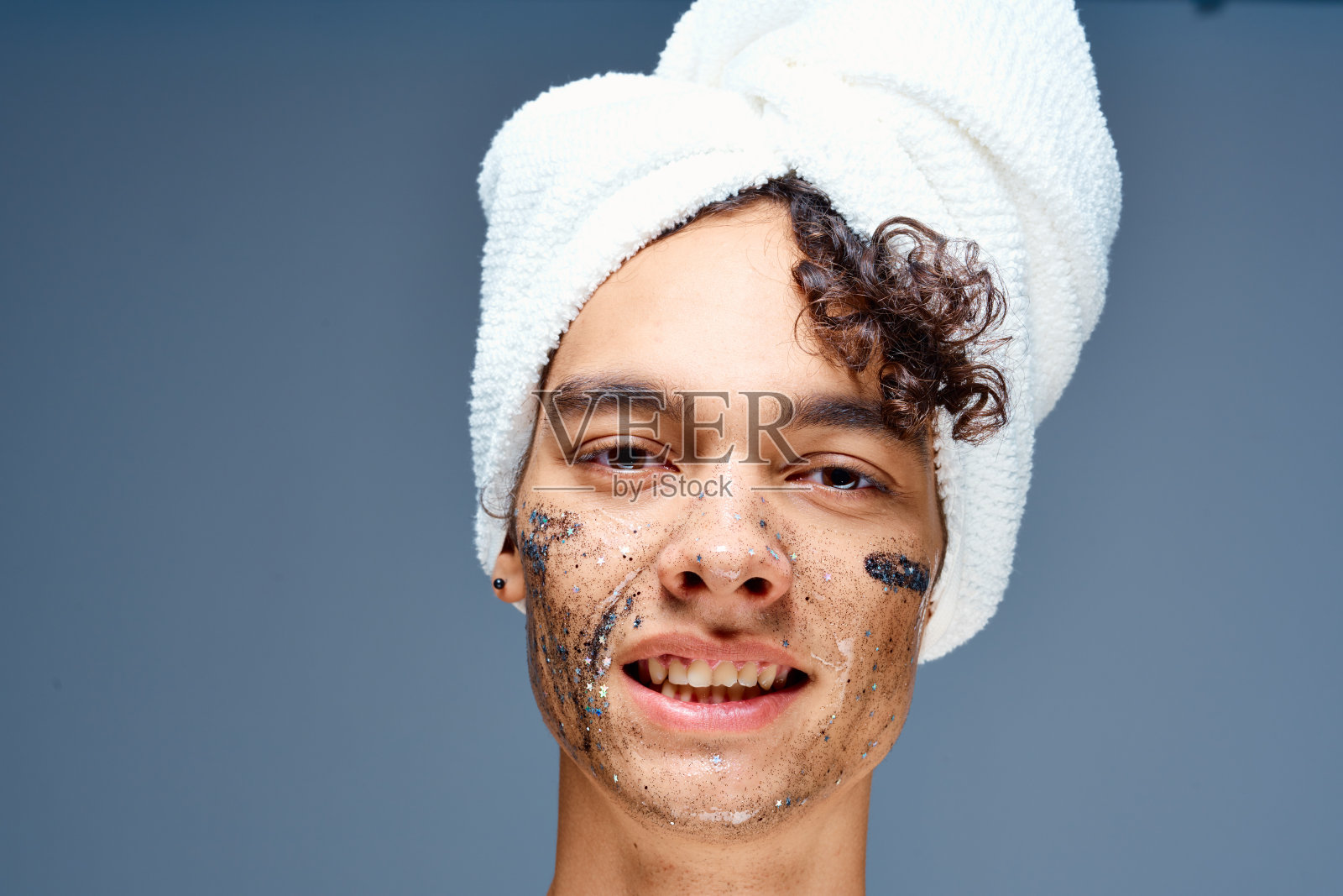 一个开朗的家伙，光着肩膀，头上裹着毛巾，脸上戴着黑色面具照片摄影图片