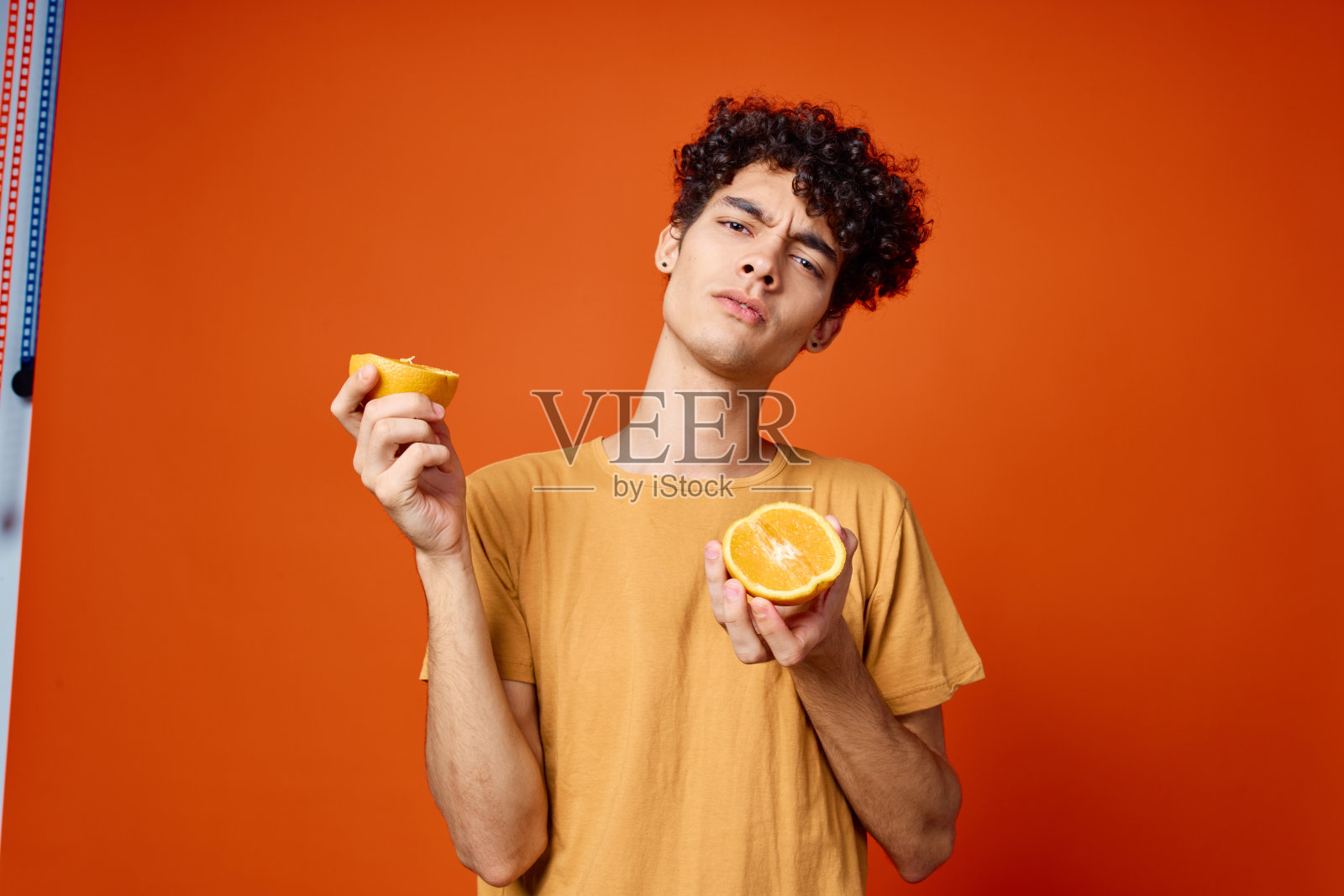 卷发的男人手里拿着橘子工作室孤立的背景照片摄影图片