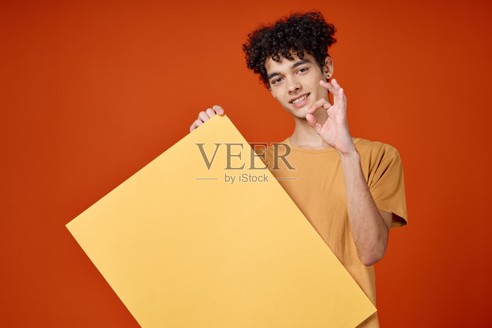 一个开朗的卷发男人手里拿着广告工作室的海报照片摄影图片