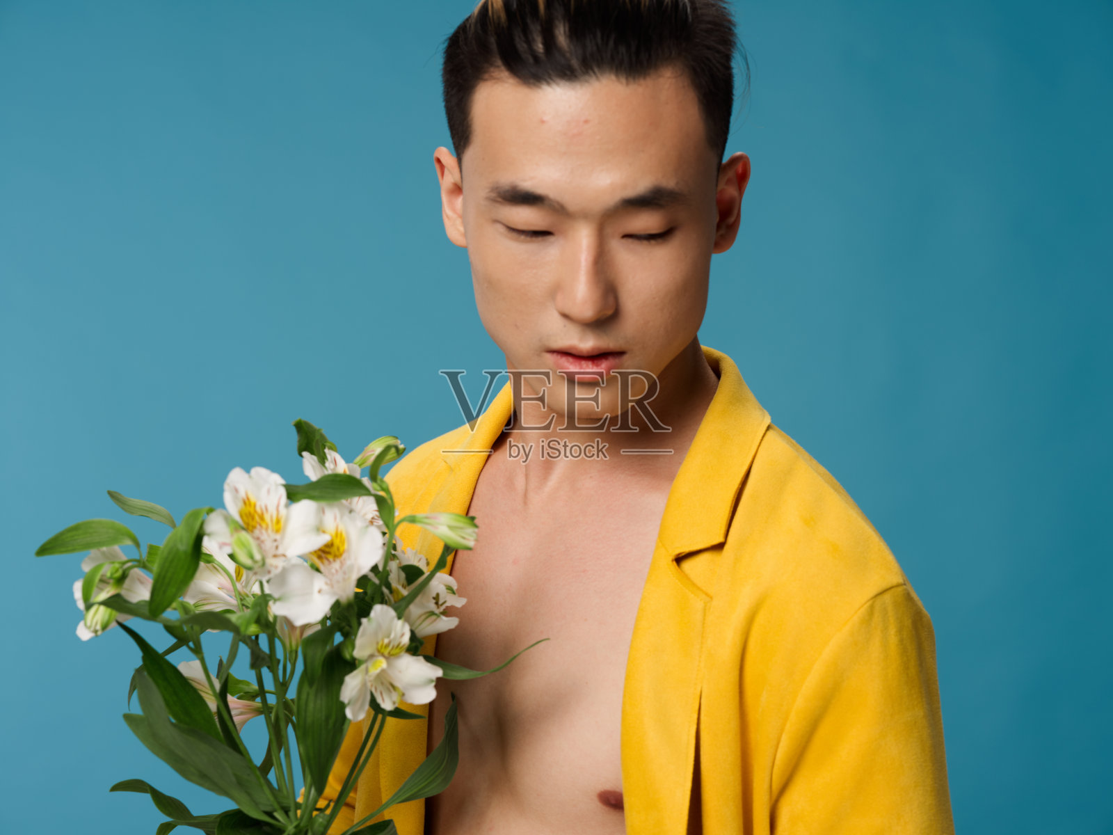 一个浪漫的男人，穿着黄色外套，赤裸着身子，拿着一束花，手里拿着礼物照片摄影图片