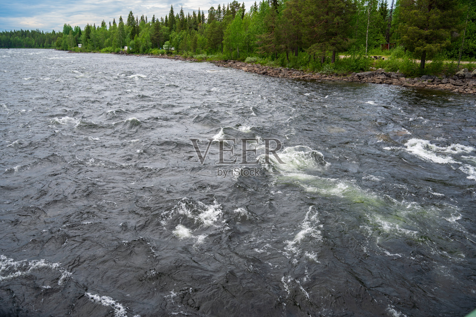 北河在茂密的绿色森林与多云的天空。照片摄影图片