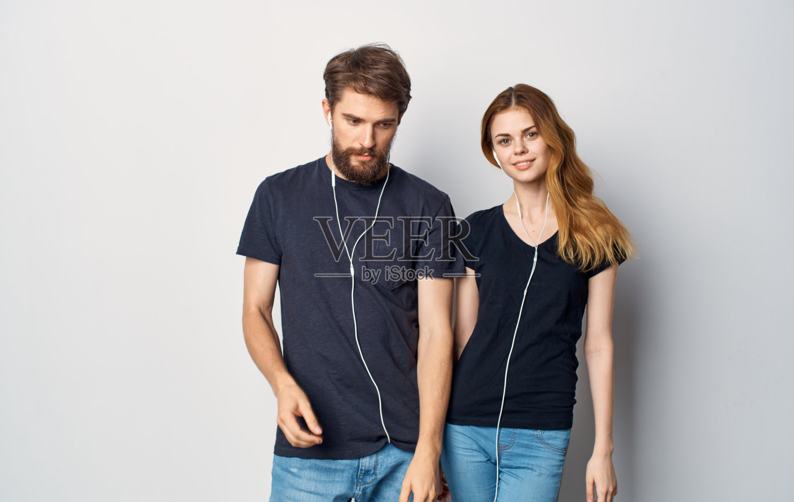 年轻夫妇穿着黑色t恤，戴着耳机听着科技音乐照片摄影图片