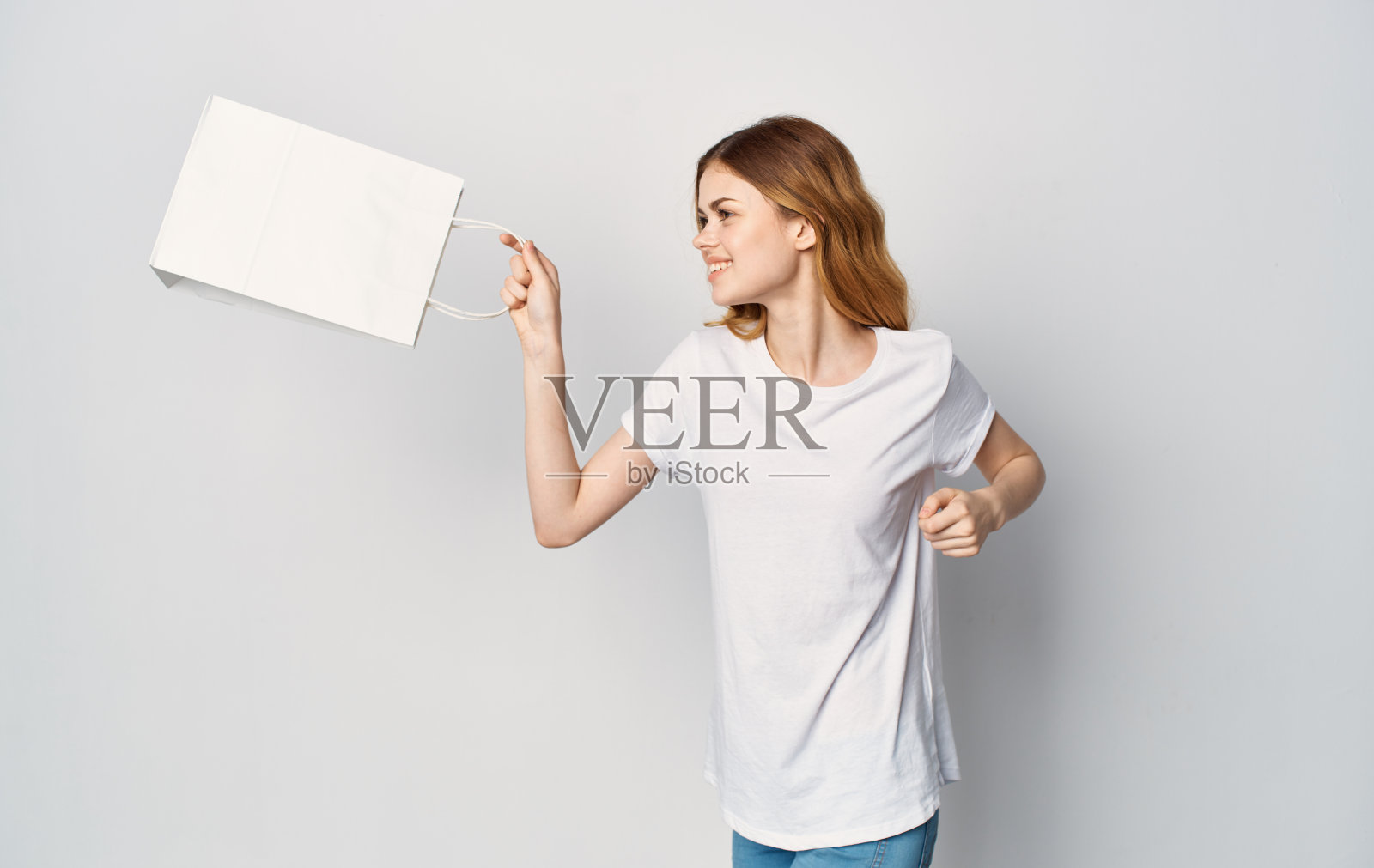 一个穿着白色t恤，手里拿着包裹的女人在孤独的背景下购物照片摄影图片