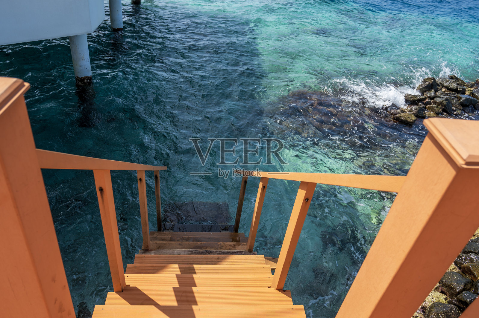 橙色的台阶通向淡蓝色的海水。照片摄影图片