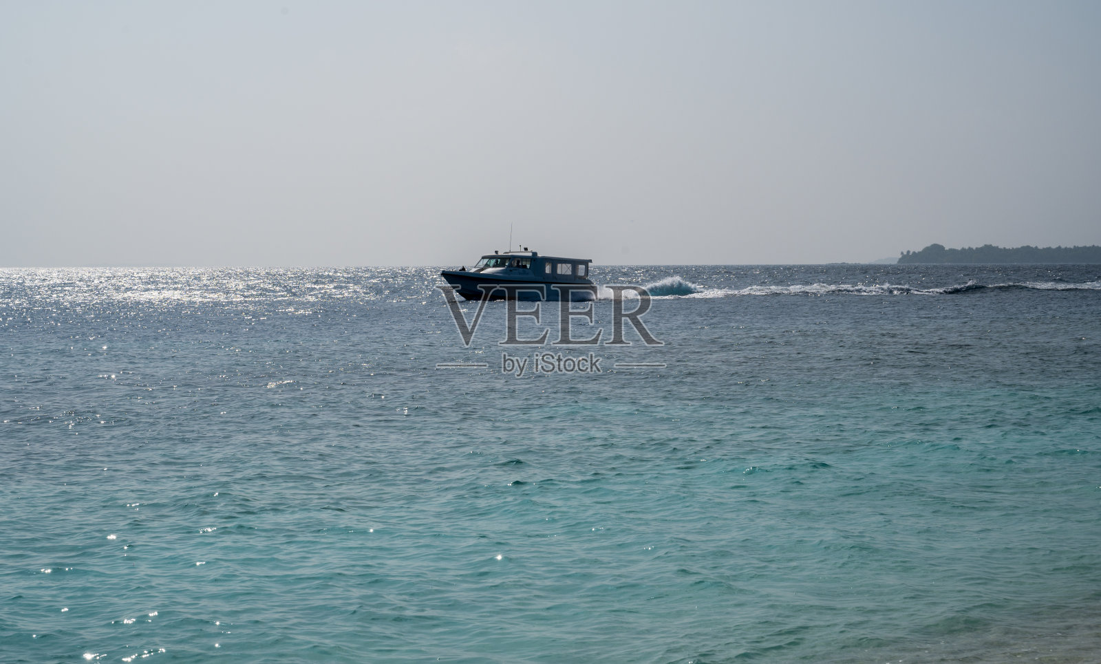 一条白色的小船在海面上漂得很快。照片摄影图片