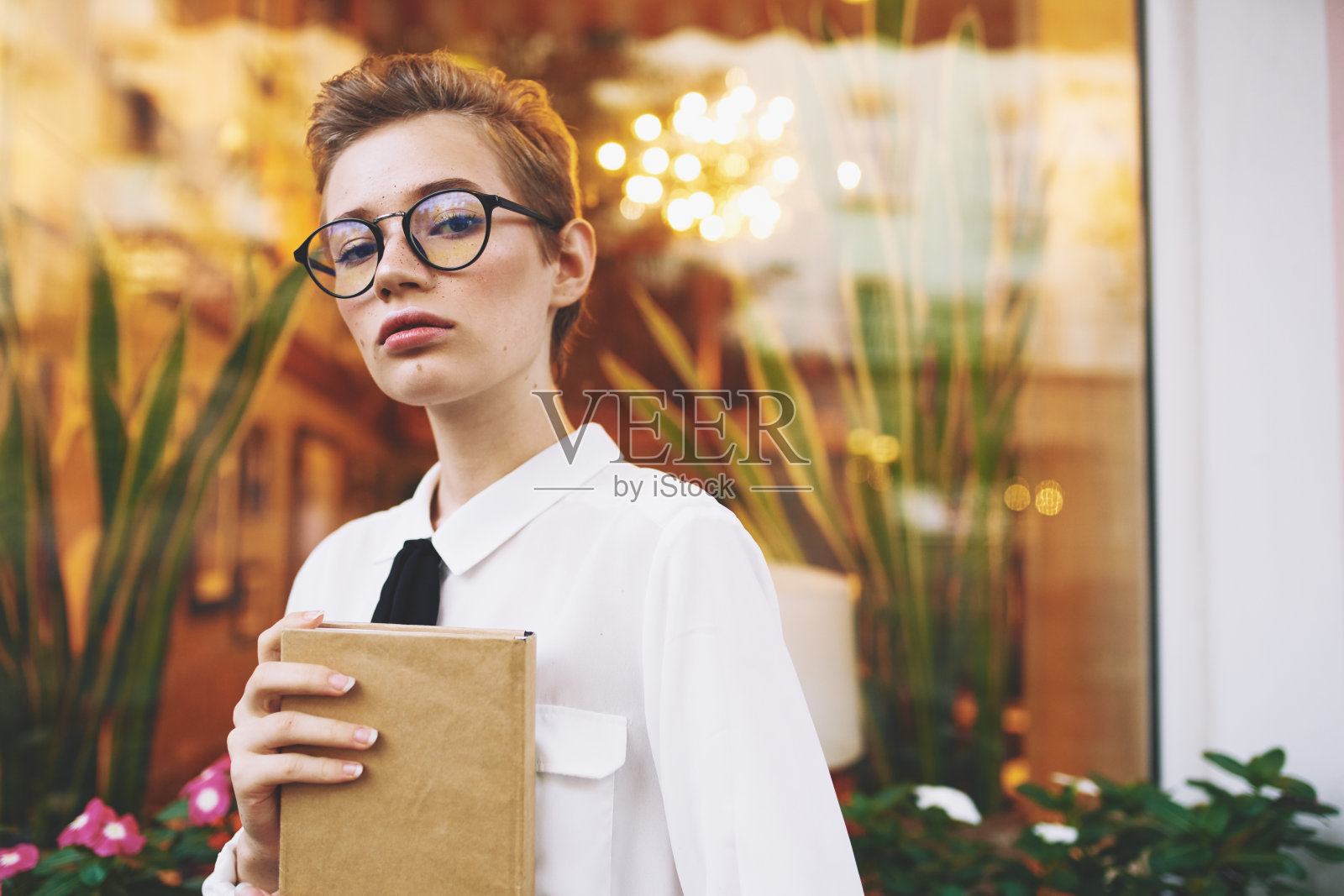 聪明的短发女人手里拿着记事本，脸上戴着眼镜照片摄影图片