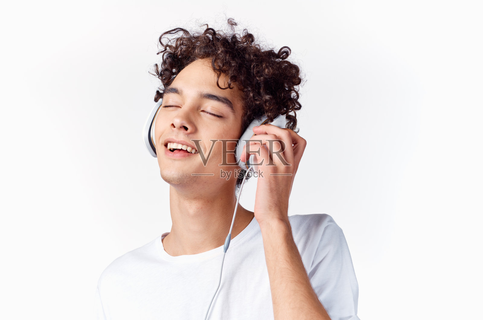 一个情绪化的卷发男人，戴着耳机听着音乐，背景很淡照片摄影图片