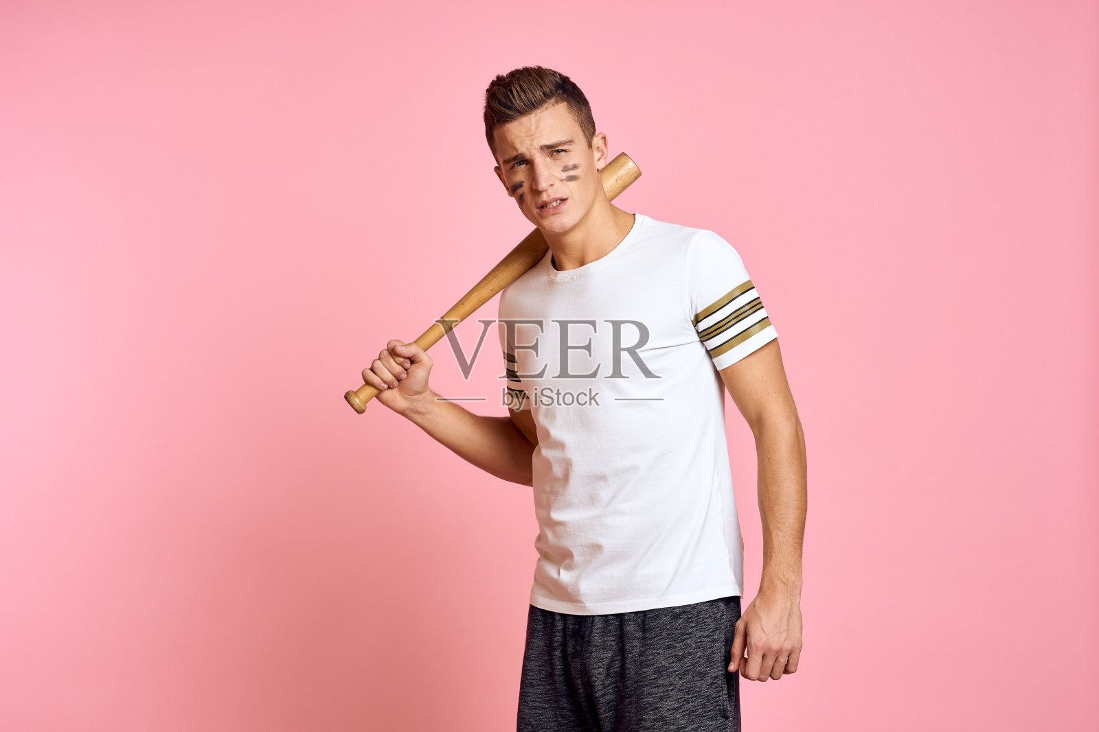 精力充沛的男子带着一只蝙蝠，身穿粉红色背景t恤，脸上化妆黑线，具有攻击性照片摄影图片