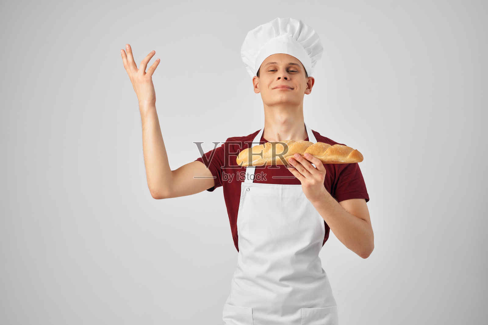 情绪激动的男厨师戴着白围裙，手里拿着烤面包做饭照片摄影图片